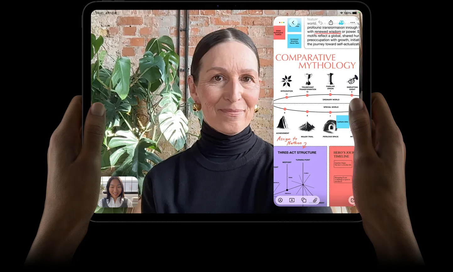 左右两只手拿着横屏放置的深空黑色 iPad Pro，正面外观展示圆角设计、黑色显示屏边框，屏幕显示 FaceTime 通话画面，以及一款教育类 app，呈现带有文字、图表和手写笔记的《比较神话学》演示文稿。