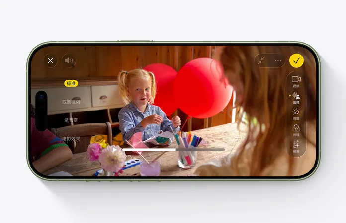 iPhone 17 正面外观，展示正在使用混音功能拍摄视频，画面是孩子坐在桌前做手工，身后有两只红色气球。